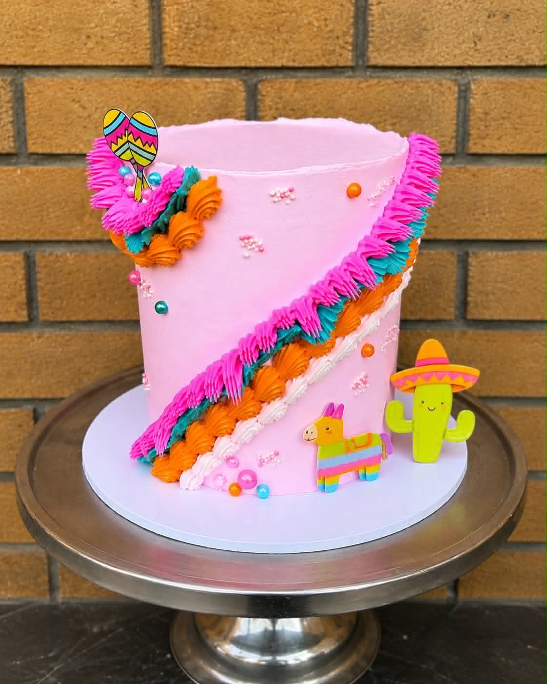 Pink fiesta birthday cake with colourful fringe buttercream, pinata and cactus decorations